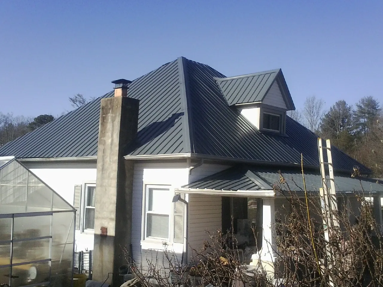 Dark blue standing seam metal roof on a white farmhouse with dormer — Slate & Tile Roof Repair by Roofing Brothers in Palm Springs
