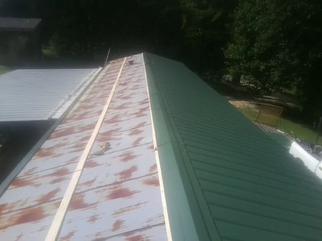 Old rusted panels beside newly installed green metal roofing — Wind Damage Roof Repair by Roofing Brothers in Palm Springs