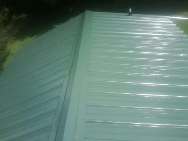 New green metal panels meeting at the ridge of a roof — Flat Roof Repair work by our crew in Palm Springs