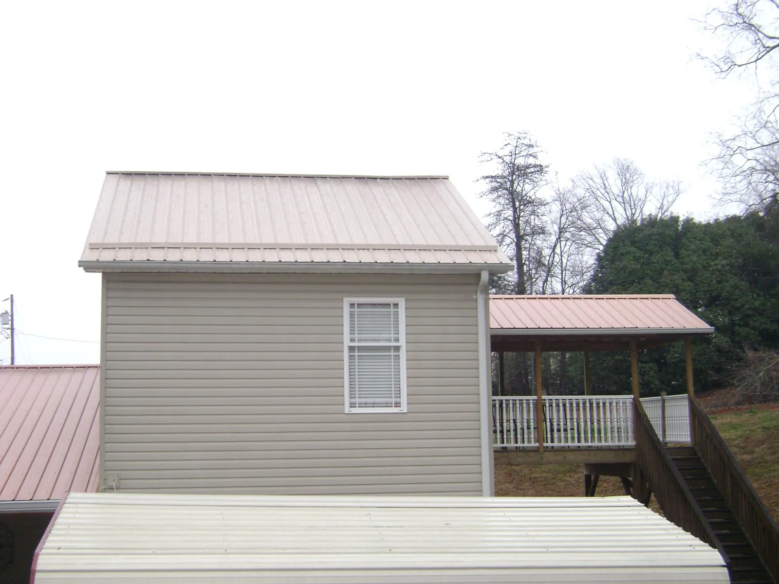 Tan metal roofs on a two story addition and attached porch, from a Roof Replacement job in Palm Springs