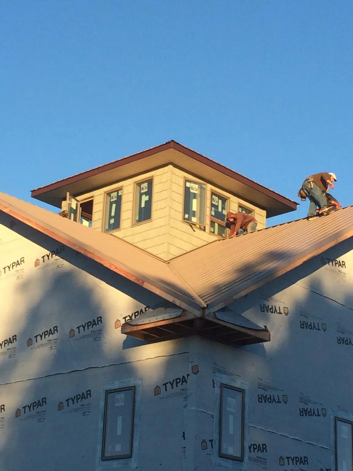 Roofers working around a rooftop cupola on a new metal roof at sunset — Roof Waterproofing in Palm Springs by Roofing Brothers